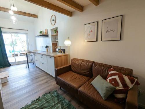 un salon avec un canapé marron et une cuisine dans l'établissement Studio pour 2 à 10min de la mer, à Saint-Nazaire