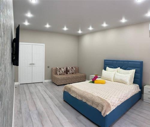 sypialnia z niebieskim łóżkiem i kanapą w obiekcie VIP апартаменты в центре города w mieście Kustanaj