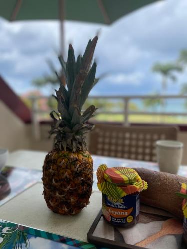 a pineapple sitting on a table next to a container of salsa at Appartement Madinina 6 personnes vue sur mer dans village vacances in Sainte-Luce