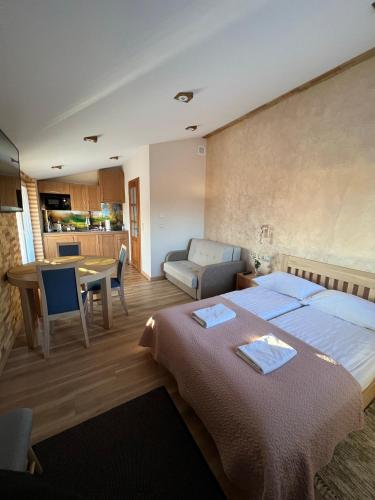 a bedroom with two beds and a table and a kitchen at Apartament Vanessa 2 u podnóża gór, nad jeziorem Czorsztyńskim in Harklowa