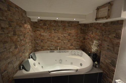 a bath tub in a bathroom with brick walls at Haus Erli in Mittenwald