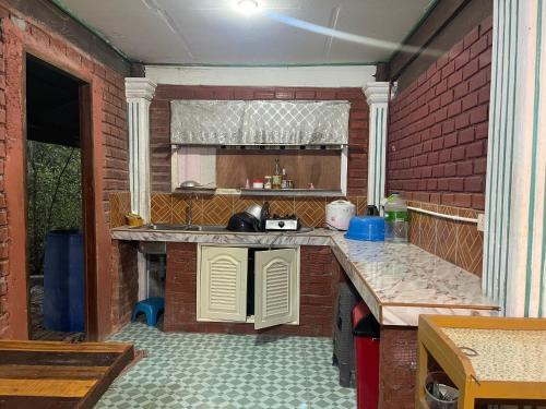 a kitchen with a counter and a brick wall at Hillmyna garden home stay in Ko Por