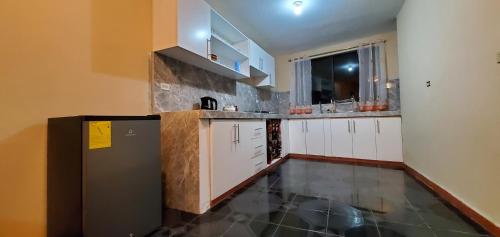 a kitchen with white cabinets and a black refrigerator at Departamento en Cuenca, 2 habitaciones y parqueo gratis in Cuenca