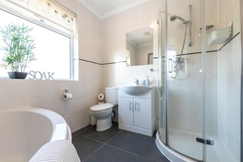 a bathroom with a tub and a sink and a toilet at Cheerful 3-bedroom Douglas house with patio in Southampton