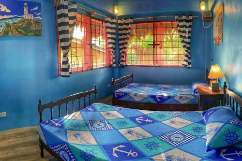 two beds in a room with blue walls and windows at Beach House-Casita in Calatagan with pool ( for 6) in Calatagan
