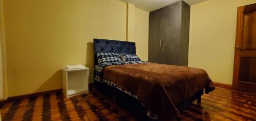 a bedroom with a bed with a blue head board at Departamento en Cuenca, 2 habitaciones y parqueo gratis in Cuenca