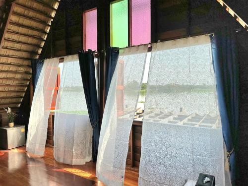 a group of windows with curtains in a room at RuenKijja in Ban Kroen