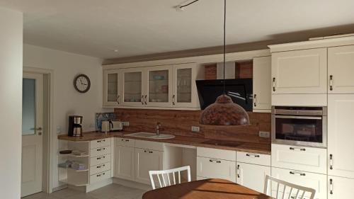 a kitchen with white cabinets and a table and a clock at FeWo mit Heimatgefühl in Ratekau