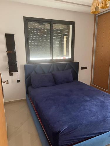 Ideal appartement de vacances في Plage de Mehdia: سرير أزرق في غرفة مع نافذة