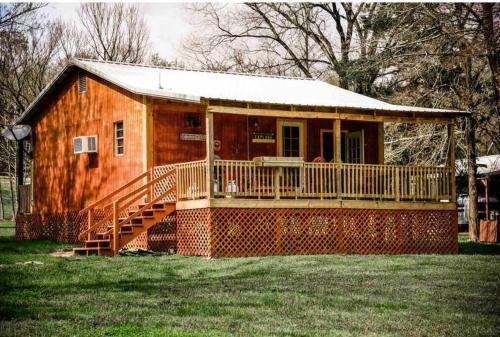 a small wooden house with a porch and a deck at Caddo Cabin on Collier Creek in Norman