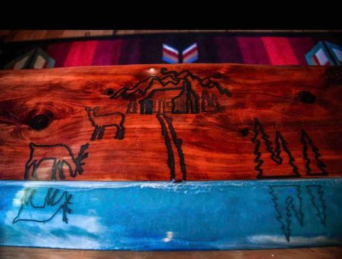 a wooden cutting board with a painting on it at Caddo Cabin on Collier Creek in Norman