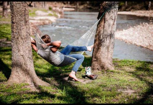 a woman laying on a hammock between two trees at Caddo Cabin on Collier Creek in Norman