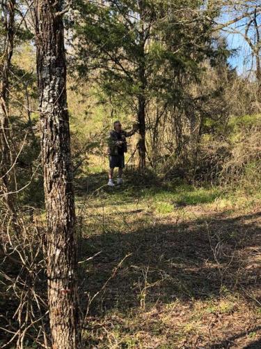 a man is standing in the woods near a tree at Caddo Cabin on Collier Creek in Norman