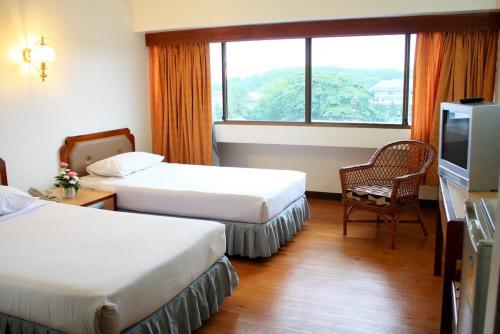 um quarto de hotel com duas camas e uma televisão em Thumrin Hotel em Trang
