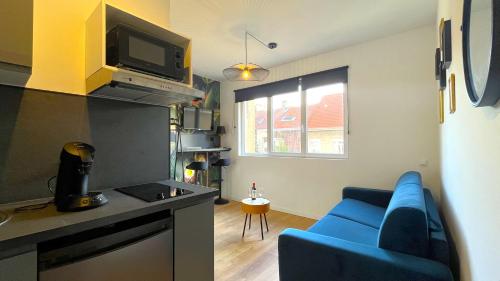 un salon avec un canapé bleu et une cuisine dans l'établissement Jungle Boogie, à Calais