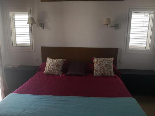 a bedroom with a bed with red sheets and two windows at Lemon tree in Tías