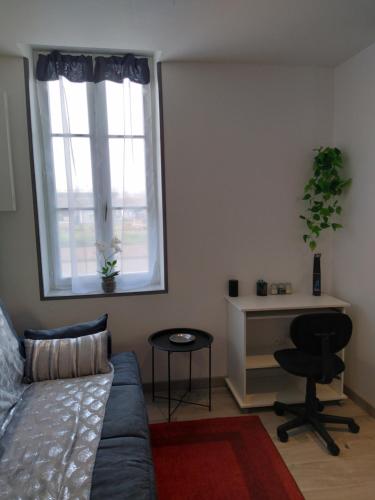a bedroom with a couch and a desk and a window at Cassiopée 3*** in Fourchambault