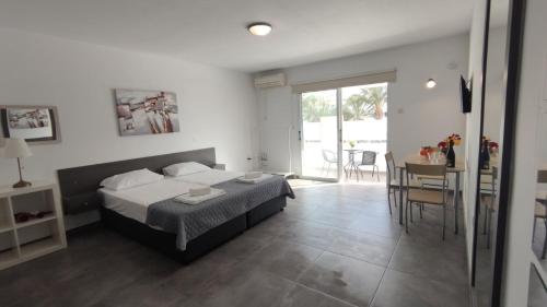 a bedroom with a bed and a dining room with a table at Nissi avenue studio in Ayia Napa
