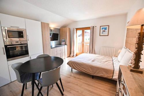 1 dormitorio con 1 cama y 1 mesa en una habitación en Le balcon des neiges, en Praz-sur-Arly