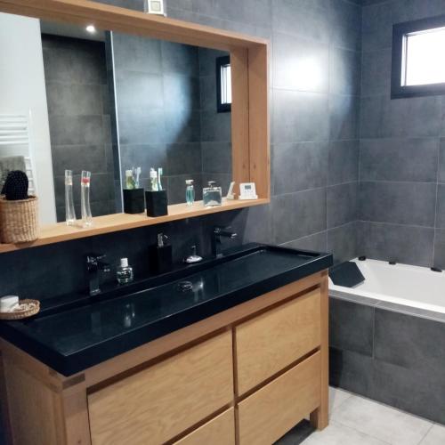 La salle de bains est pourvue d'un lavabo noir et d'une baignoire. dans l'établissement Chambre chez l'habitant Aux portes du Mans Evénements circuits du Mans, à Rouillon