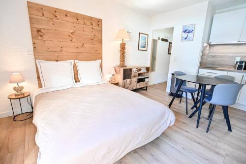 Un dormitorio con una gran cama blanca y una mesa en Le balcon des neiges, en Praz-sur-Arly