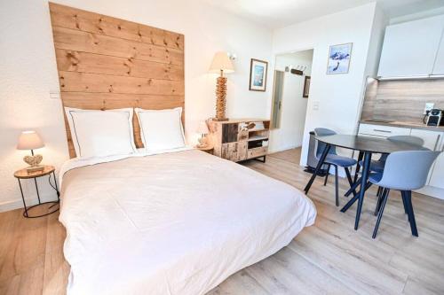 a bedroom with a large white bed and a table at Le balcon des neiges in Praz-sur-Arly