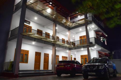 a building with two cars parked in front of it at Rathna Holiday Resort in Kataragama