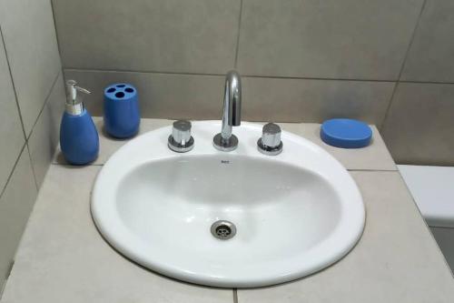a white sink in a bathroom with blue bottles at Cabaña de campo La Tabanerina in Salto de las Rosas