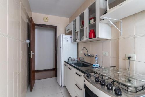 a small kitchen with a sink and a refrigerator at Family Space Curitiba/vaga de garagem Gratis in Curitiba