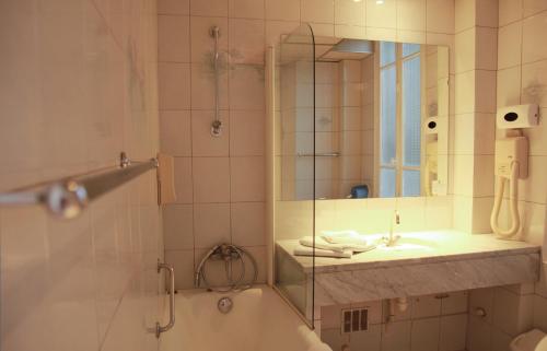 La salle de bains est pourvue d'une baignoire, d'un lavabo et d'une douche. dans l'établissement Hôtel De La Cathédrale, à Reims