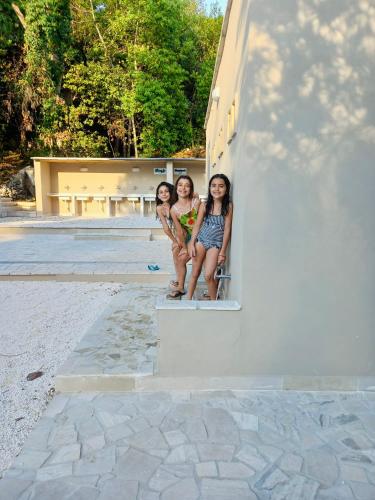 three girls sitting on a ledge of a building at Baia Dei Micenei in Otranto