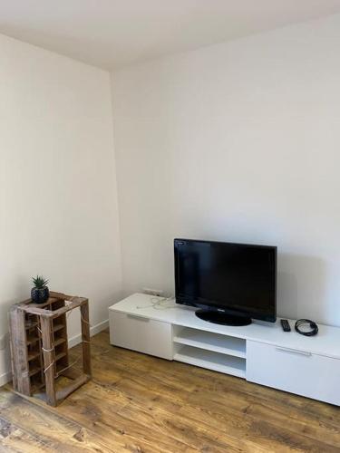 un téléviseur à écran plat posé sur un centre de divertissement blanc dans l'établissement Chez mémère, Vosges, à Saint-Étienne-lès-Remiremont