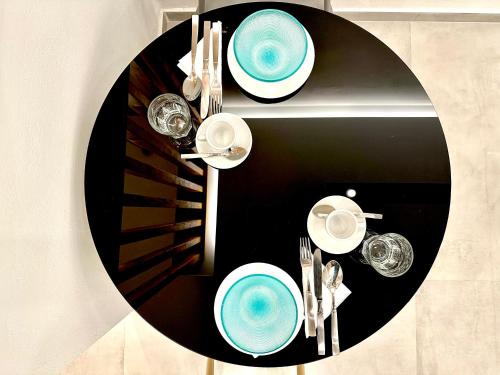 un tavolo nero con piatti blu e bicchieri sopra di Urban Luxus Studio I a Heraklion