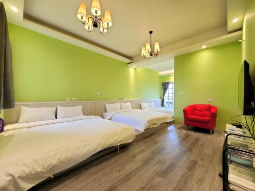 zwei Betten in einem Zimmer mit grünen Wänden und einem roten Stuhl in der Unterkunft 甜蜜的家包棟民宿 in Yilan