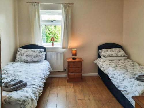 two beds in a small room with a window at Snowdrop Cottage - W43121 in Goxhill