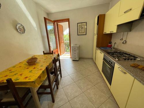 a kitchen with a wooden table and a dining room at Appartamenti Su Pasiu in Chia