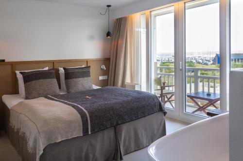 Schlafzimmer mit einem Bett und einer Badewanne sowie einem Balkon in der Unterkunft Noordzee, Hotel & Spa in Cadzand-Bad