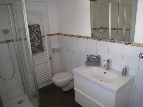 a white bathroom with a toilet and a sink at Gästehaus München in Schönau am Königssee
