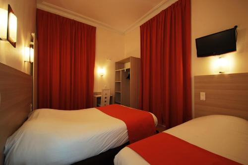a hotel room with two beds and red curtains at Hôtel De La Cathédrale in Reims