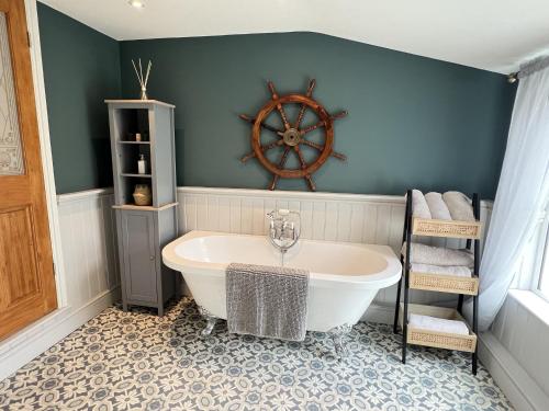 uma casa de banho com banheira e uma roda de navio na parede em Luxurious Victorian villa with parking sleeps six em Bury Saint Edmunds