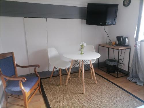 una mesa blanca y sillas en una habitación con TV en Chez Sophie et Thibault en Sceaux-du-Gâtinais