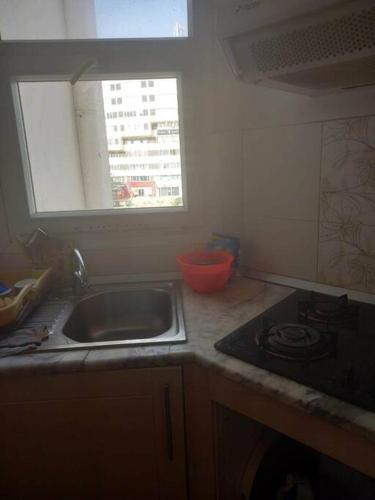 a kitchen with a sink and a stove and a window at Appartement plein Centre Urbain in Tunis