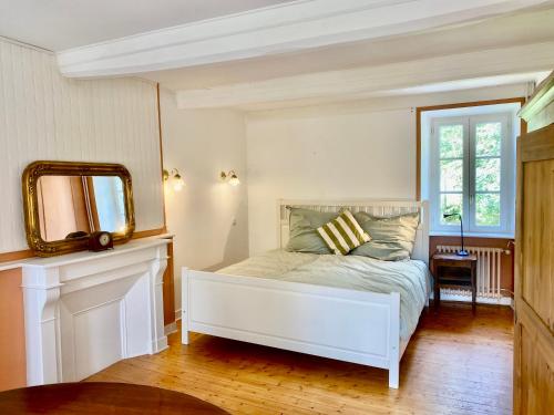 Schlafzimmer mit einem weißen Bett und einem Spiegel in der Unterkunft Hübsches Landhaus der Familie mit eigenem Garten in Heugueville-sur-Sienne