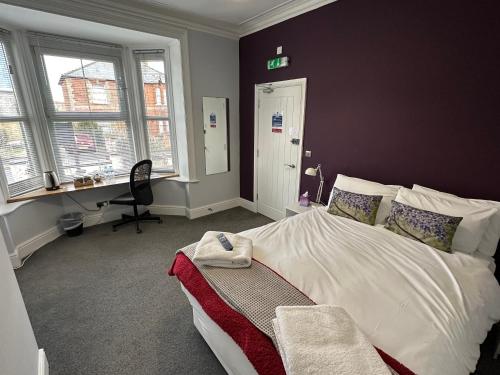 a bedroom with a bed and a desk and windows at Arlan House, Central Basingstoke Hotel in Basingstoke