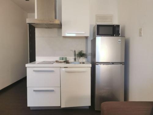 a white kitchen with a refrigerator and a microwave at Elite Pod 5516 Knightsbridge Residences in Manila