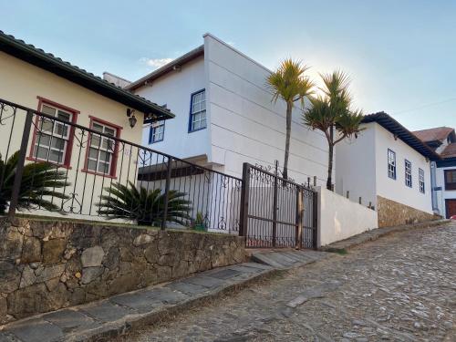 een wit huis met palmbomen naast een straat bij Casa no Centro Histórico de Catas Altas in Catas Altas