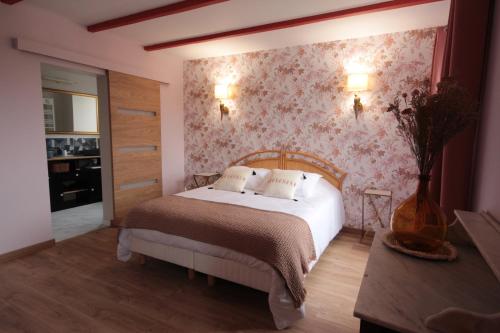 una camera da letto con un letto e carta da parati floreale di Le Manoir de Kérofil ** Gîte et chambres d'hôtes ** 