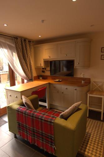 a kitchen with white cabinets and a couch and a counter at Reayrt Ny Marrey in Kirkmichael