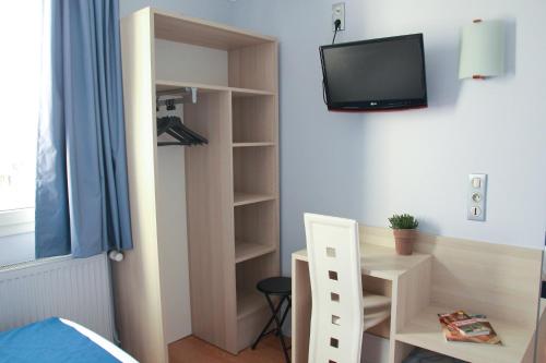 a bedroom with a desk and a tv on the wall at Hôtel De La Cathédrale in Reims