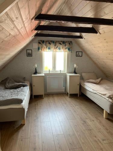 a attic bedroom with two beds and a window at Villa Ulvatorp nära Varberg och Ullared in Veddige